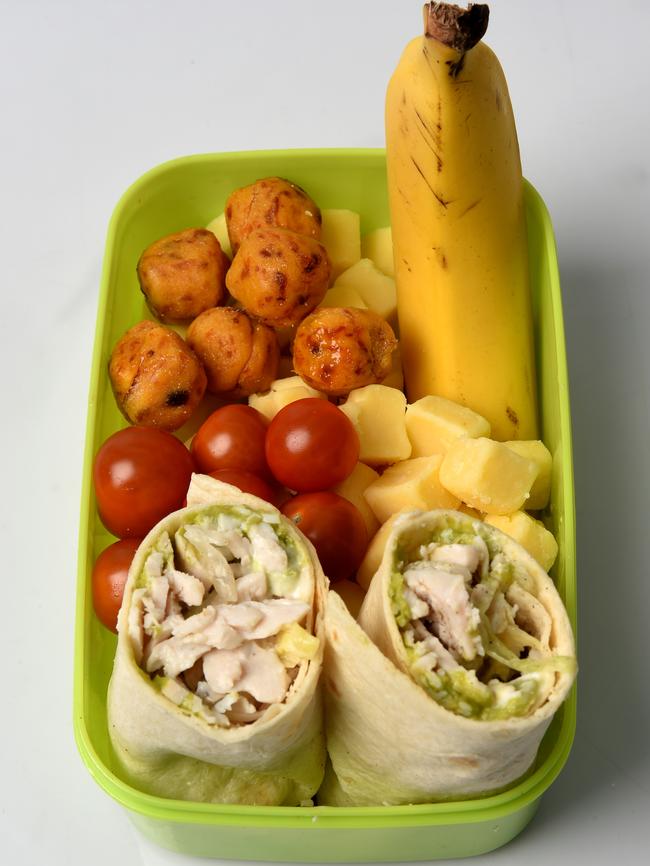 Homemade apricot and date bites, roast chicken, corn, avocado and lettuce in mountain bread wraps, cherry tomatoes, cubes of tasty cheese, and a banana.