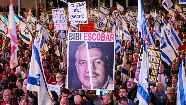 A demonstrator holds a sign depicting a mashup of the faces of Israeli Prime Minister Benjamin Netanyahu and late Colombian drug lord Pablo Escobar during an anti-government demonstration in Tel Aviv.