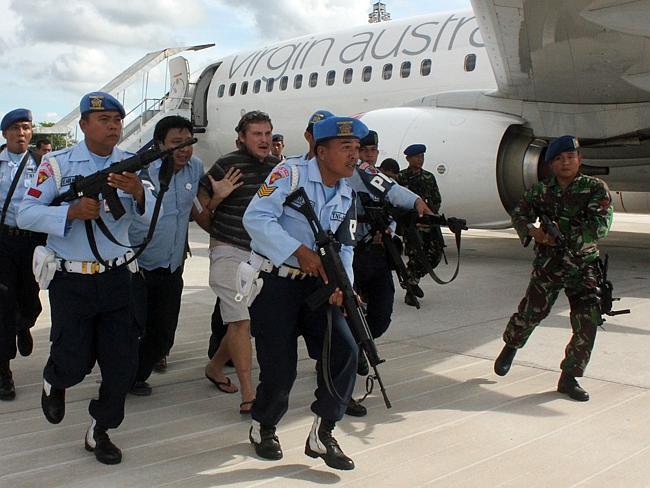 Handcuffed and being led away from plane at gunpoint ... Matt Lockley is taken from the Virgin Australia flight at Denpasar.