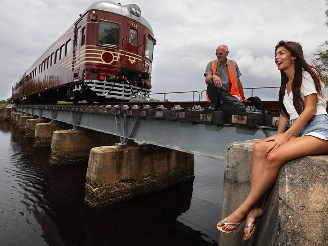 30/11/2017: A 1947 railcar converted to electric and solar power, stopped and at rest during a test run, as train driver Robert Jarvis chats with local Coco Allen, 22, who as a child played here on the old disused railway bridge over the Belongil Creek, is excited for the town to have a train once again in Byron Bay, NSW. The not for profit Byron Bay Railroad Co. has been set up to ferry passengers from the town centre to nearby northern beaches, and has become the worlds first "solar powered" train in an effort to appease local green concerns, using the existing, but closed, rail corridor. Lyndon Mechielsen/The Australian