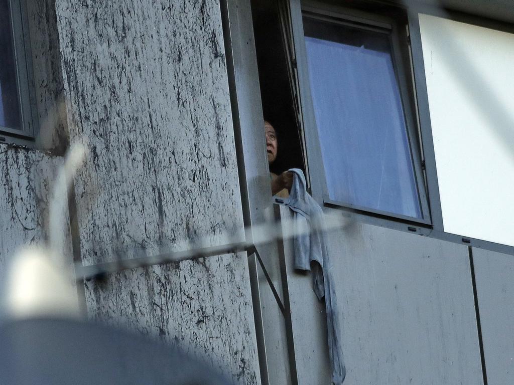 A resident peers out of a window of the Grenfell Tower. Picture: AP/Matt Dunham