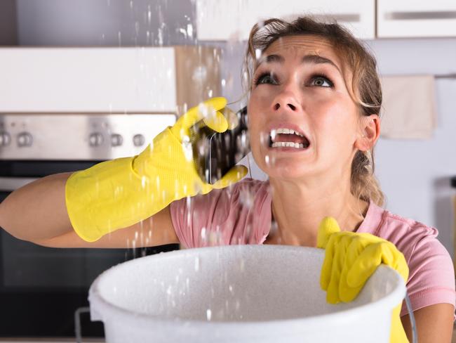 Shocked Woman Calling Plumber While Collecting Water Leaking From Ceiling Using Utensil