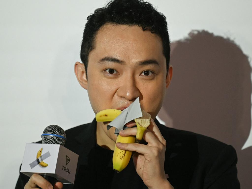 Chinese-born crypto founder Justin Sun eats a banana artwork composed of a fresh banana stuck to a wall with duct tape. Picture: Peter Parks/AFP