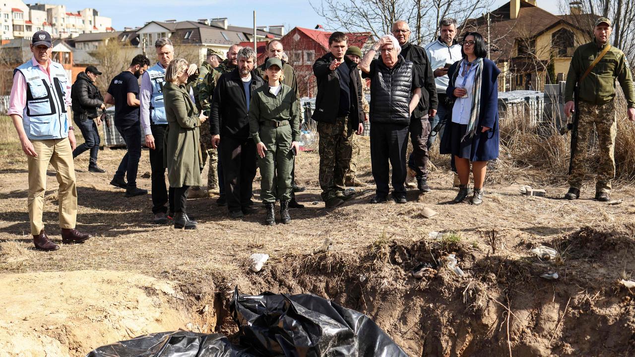 UN humanitarian chief Martin Griffiths (5th R) reacts at the site of a mass grave in Bucha. Photo by RONALDO SCHEMIDT / AFP