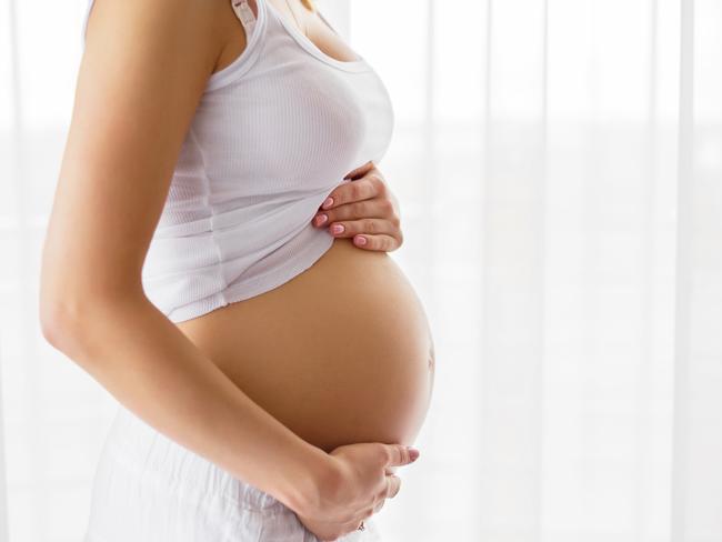 Pregnant woman standing next to window