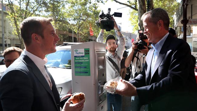 Bill Shorten giving a hot cross bun to Channel 10's Jonathan Lea after visiting the Salvation Army's Lighthouse Cafe in Melbourne. Picture: Kym Smith