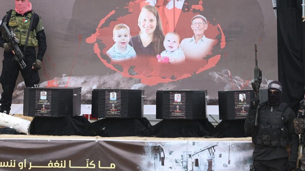 Armed Hamas militants stand next to the coffins on stage before handing over the bodies of four Israeli hostages to the Red Cross in Khan Yunis.