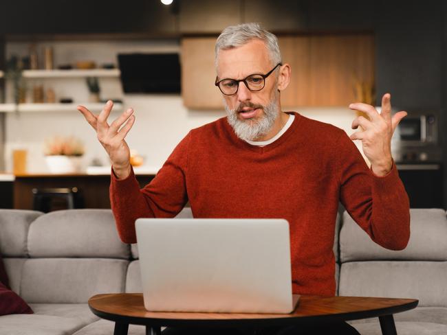 Angry mature middle-aged man businessman freelancer talking with clients colleagues business partners online on laptop, solving problems, explaining at home remotely; investing investor superannuation money generic