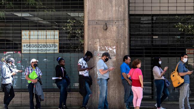 People wear face masks as they line up to get their unemployment insurance outside the Unemployment Funds Administration Society headquarters in Santiago in Chile. Picture: AFP