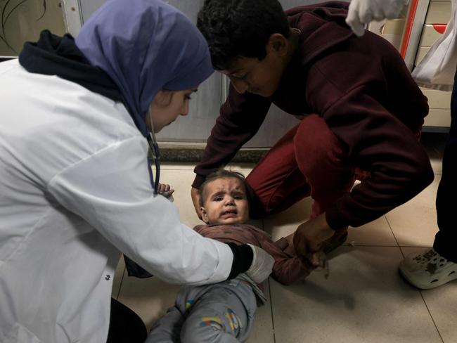 A medic checks a Palestinian child on the floor at the Nasser Hostpial in Khan Yuni. Picture: AFP