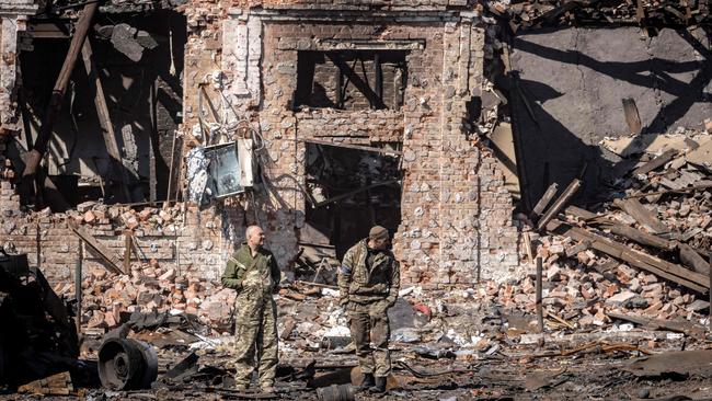 TUkrainian troops stand next to rubble of a destroyed building in the northeastern city of Trostianets. Picture: AFP