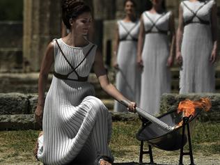 TOPSHOT - Actress Katerina Lechou performing as the high priestess lights the Olympic flame at the Temple of Hera  on April 21, 2016 during the lighting ceremony of the Olympic flame in ancient Olympia, the sanctuary where the Olympic Games were born in 776 BC.  The Olympic flame was lit today and solemnly sent off carrying international hopes that Brazil's political paralysis will not taint the Rio Games that start in barely 100 days. / AFP PHOTO / ARIS MESSINIS