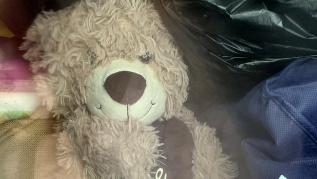 A child’s Teddy Bear sits on the floor well amongst bags of clothes of a green Toyota Ute which was found parked at the crime scene at Burleigh Stocklands Shopping Centre after a woman was found dead inside a charity clothing bin. Picture: NCA NEWS WIRE / Scott Powick