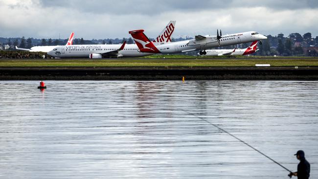 Qantas and Virgin Australia planes travel down the runway at Sydney Airport. Picture: David Gray/AFP