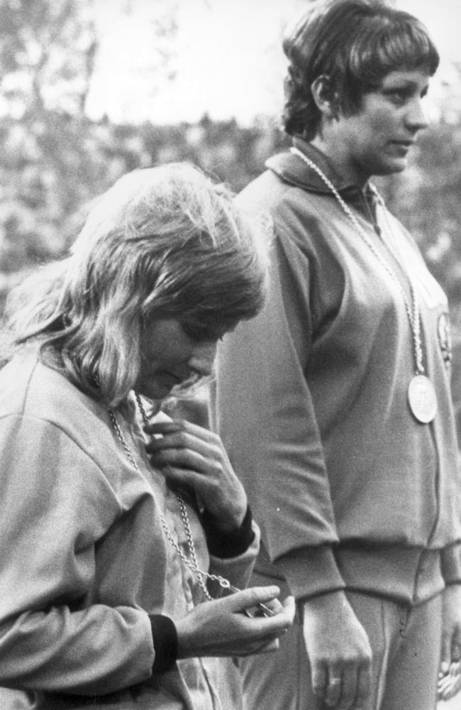 Raelene Boyle looks at her silver medal as she stands next to East Germany’s Renate Stecher on the dais in Munich.