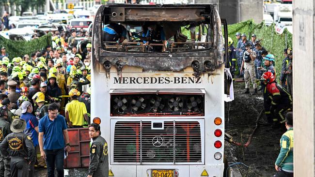 Rescue workers and firefighters surround a burnt-out bus that was carrying students and teachers on the outskirts of Bangkok. Picture: AFP