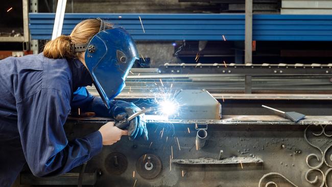 Young Female Welder Working In Factory Wearing Protective Safety Gear  Australian manufacturing workers generic, blue collar