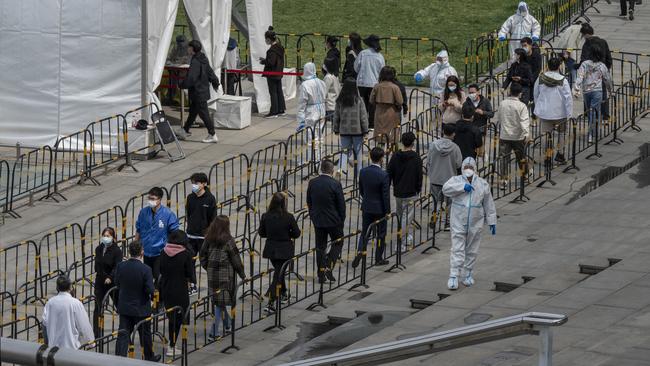 Security guards wear protective clothing as office workers queue for Covid-19 nucleic acid tests at a makeshift testing site in Beijing, China. Picture: Getty