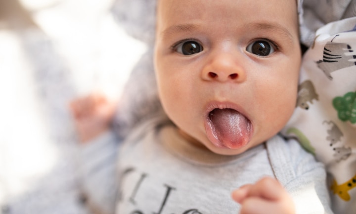 8 week old baby sticking tongue out