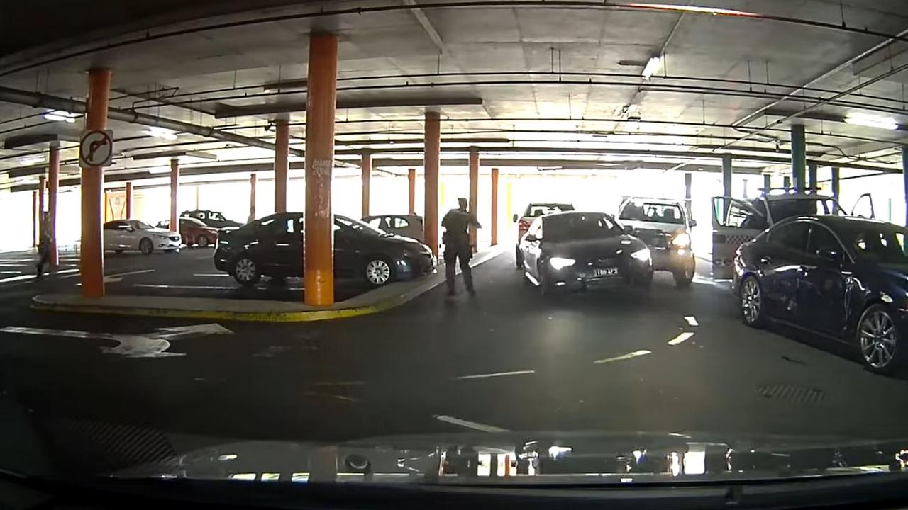 The car reverses into a ute as officers frantically try to remove him from the vehicle. A waiting police vehicle behind the driver has lights and sirens activated.