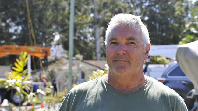 Mackays Road resident Chris Drady says something needs to be done to slow down drivers on the busy street. In the background, Essential Energy staff work to fix a broken power pole which was impacted by a crash. Picture: Tim Jarrett