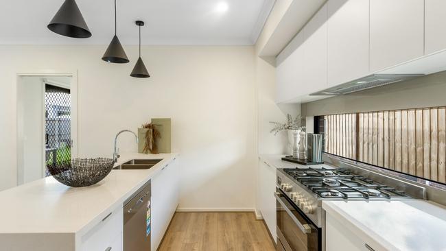 The kitchen has stone benches, crisp white cabinetry and contrasting stainless steel appliances.