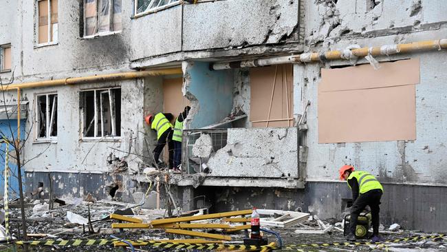 Communal services workers board up holes in walls and broken windows at a residential building damaged by shelling, in Kharkiv, on April 14. Picture: AFP.