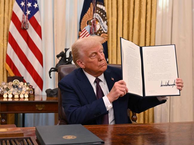 US President Donald Trump holds up an executive order he just signed to strenghten American leadership in digital financial technology, in the Oval Office of the White House in Washington, DC, on January 23, 2025. (Photo by ROBERTO SCHMIDT / AFP)