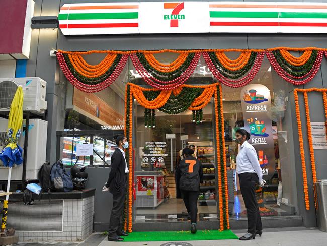 Staff members stand at the entrance of India's first 7-Eleven convenience store in Mumbai. Picture: AFP