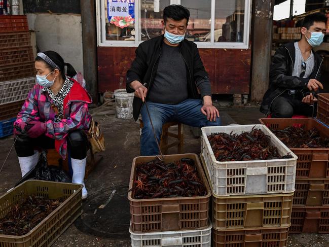 TOPSHOT - This photo taken on April 15, 2020 shows vendors wearing face masks as they offer prawns for sale at the Wuhan Baishazhou Market in Wuhan in China's central Hubei province. - China's "wet" markets have gained a bad international reputation as the coronavirus roiling the world is believed to have been born in stalls selling live game in Wuhan late last year. (Photo by Hector RETAMAL / AFP) / TO GO WITH Health-virus-China,SCENE by Jing Xuan Teng