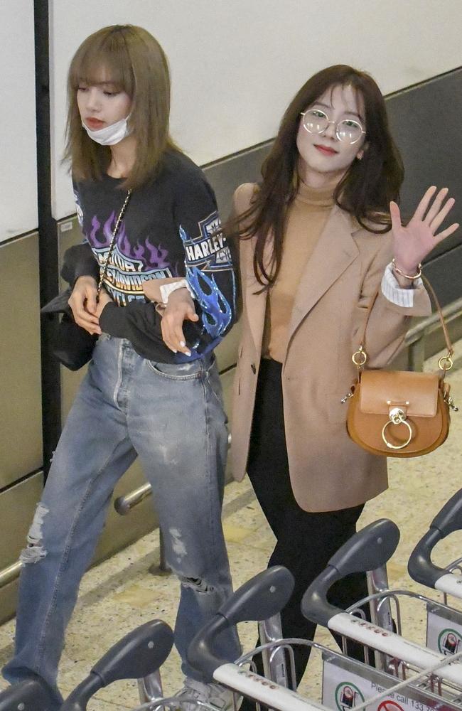 Jisoo (right) waves at fans and Lisa from the South Korean girl group Blackpink arrive at Sydney airport ahead of their Australian tour. Picture: Media Mode