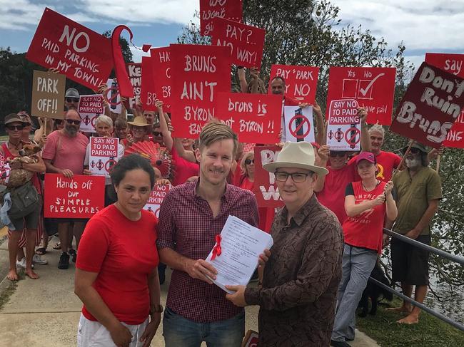 SEEING RED: Juliana Harmsen and Zac Tooth from Brunswick Heads Chamber of Commerce hand over the anti-paid parking petition containing 4,500 signatures to Byron Shire Councillor Paul Spooner, in 2017.