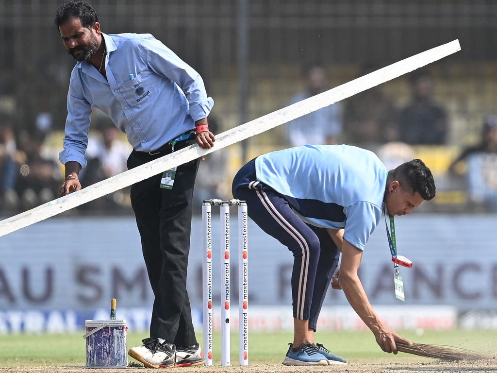 इंदौर के होल्कर स्टेडियम में पिच की सफाई करते ग्राउंड स्टाफ के सदस्य।  तस्वीरः सज्जाद हुसैन