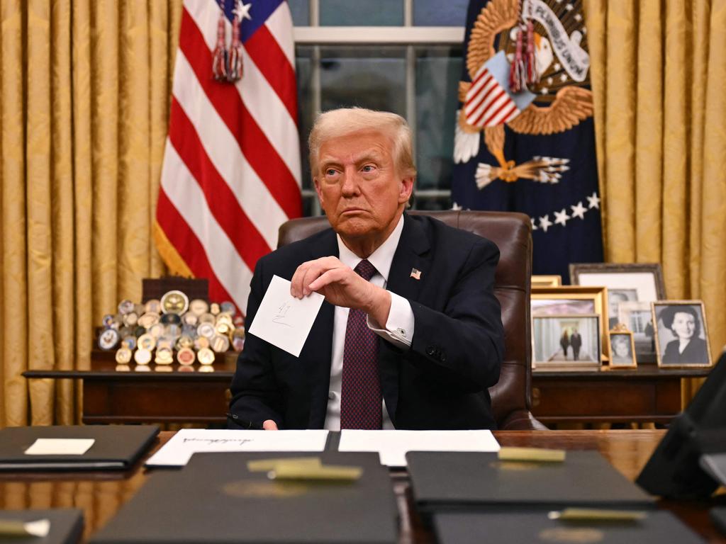 US President Donald Trump holds up outgoing President Joe Biden's letter as he signs executive orders in the Oval Office of the WHite House in Washington, DC, on January 20, 2025. (Photo by Jim WATSON / POOL / AFP)