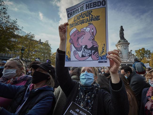 PARIS, FRANCE - OCTOBER 18: Protestors hold copies of the satirical newspaper Charlie Hebdo during an anti-terrorism vigil at Place de La Republique for the murdered school teacher Samuel Paty who was killed in a terrorist attack in the suburbs of Paris on October 18, 2020 in Paris, France. Thousands of people turned out to show solidarity and express their support for freedom of speech in the wake of Friday's attack. France launched an anti-terrorism investigation after the October 16 incident where police shot the 18 year-old assailant who decapitated the history-geography teacher for having shown a caricature of prophet Mohamed as an example of freedom of speech at the College Bois d'Aulne middle-school.  (Photo by Kiran Ridley/Getty Images)