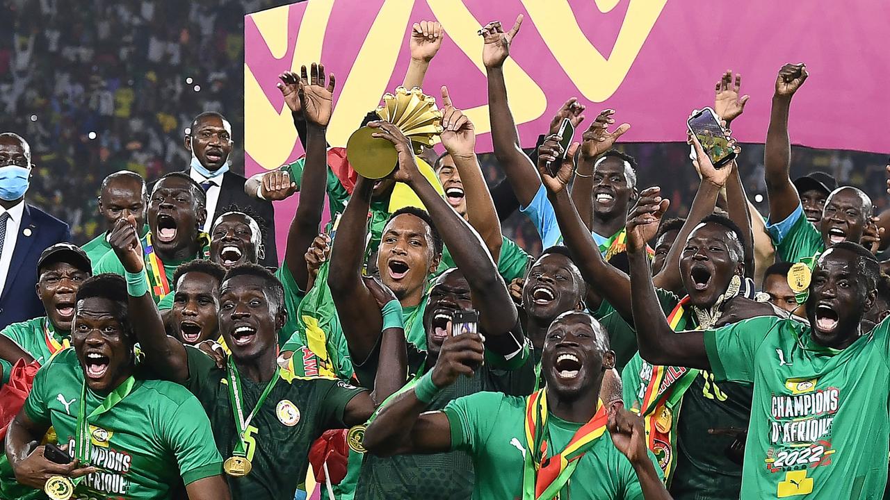 Senegal's players celebrate with the trophy after winning the Africa Cup of Nations (CAN) 2021 final football match between Senegal and Egypt at Stade d'Olembe in Yaounde on February 6, 2022. (Photo by CHARLY TRIBALLEAU / AFP)