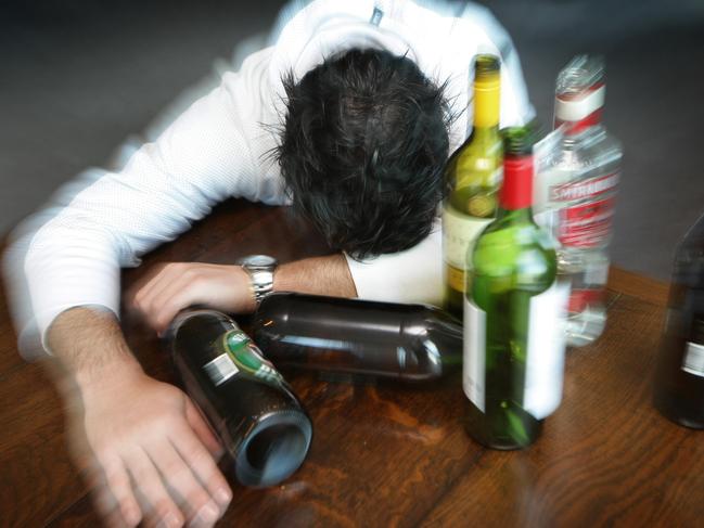 Generic photo of a man surrounded by alcohol bottles. Binge drinking. Drunk.