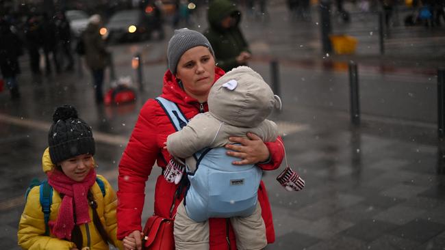 A woman walks with children at a train station in Lviv. Picture: Daniel Leal / AFP.