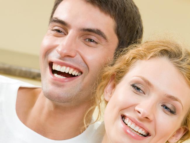 Young couple eating popcorn and watching TV together at home