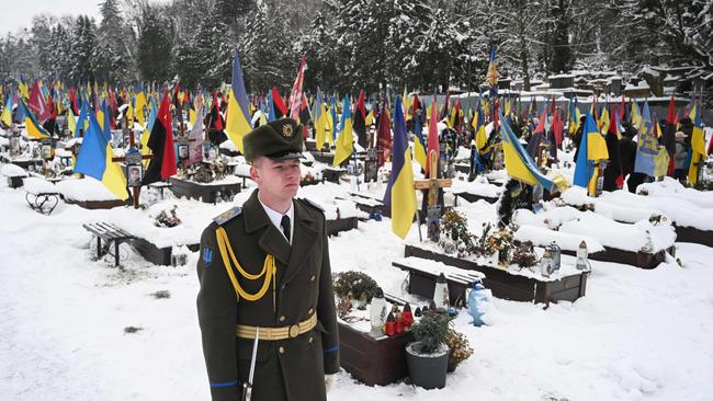 An honour guard stands next to the graves of Ukrainian soldiers. Picture: Yuriy Dyachyshyn/AFP