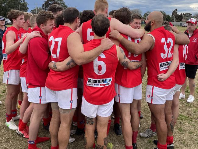 East Brighton players huddle after their rousing win.