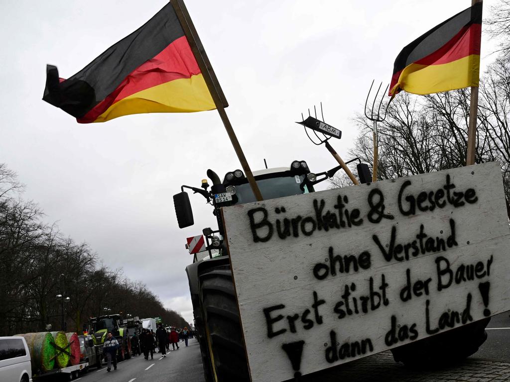 A tractor decorated with German flags and a placard reading "Bureaucracy and laws without reason - First the Farmer Dies, then the Land" during the farmers protest. Picture: AFP