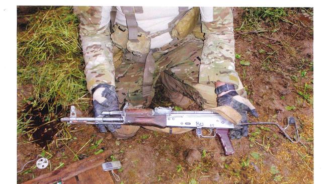 A member of the SAS holding weapons found and seized during the raid on Whiskey 108. The compound was destroyed by the ADF.