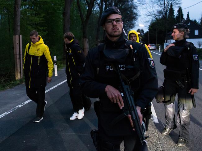 Borussia Dortmund players are escorted to a car by police after the explosions.
