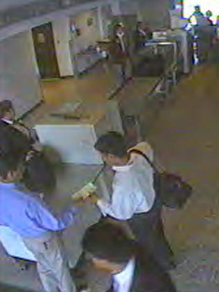 Hijackers Nawaf al-Hazmi, wearing a blue shirt, and his brother, Salem al-Hazmi, in the white shirt, wait at the security checkpoint at Dulles International Airport in Chantilly, Virginia.