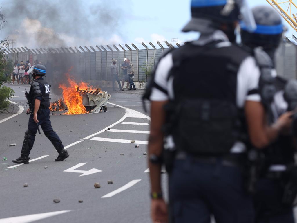 French police officers face demonstrators in Le Port on March 1, 2020, as people protest against the arrival of the passengers of the Sun Princess cruise ship on the Indian Ocean island of La Reunion without having their temperature checked. (Photo by Richard BOUHET / AFP)