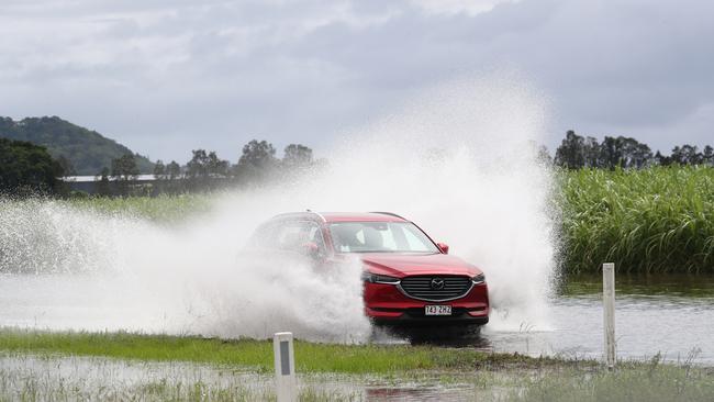 A car drives through floodwaters on Tweed Valley Way near Tumbulgum in the Tweed. Picture: Jason O'Brien