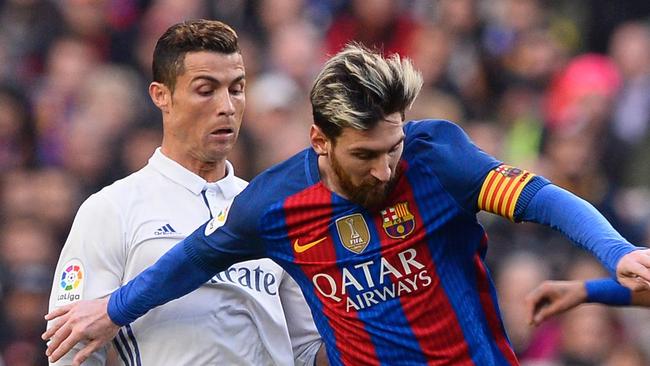 Barcelona's Argentinian forward Lionel Messi (C) vies with Real Madrid's Portuguese forward Cristiano Ronaldo.