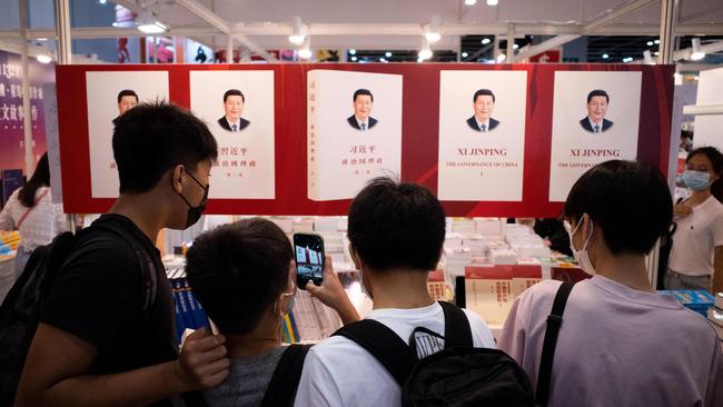 Visitors take photos of a banner illustrating a book by Chinese President Xi Jinping at a booth at the annual Hong Kong Book Fair. Picture: AFP