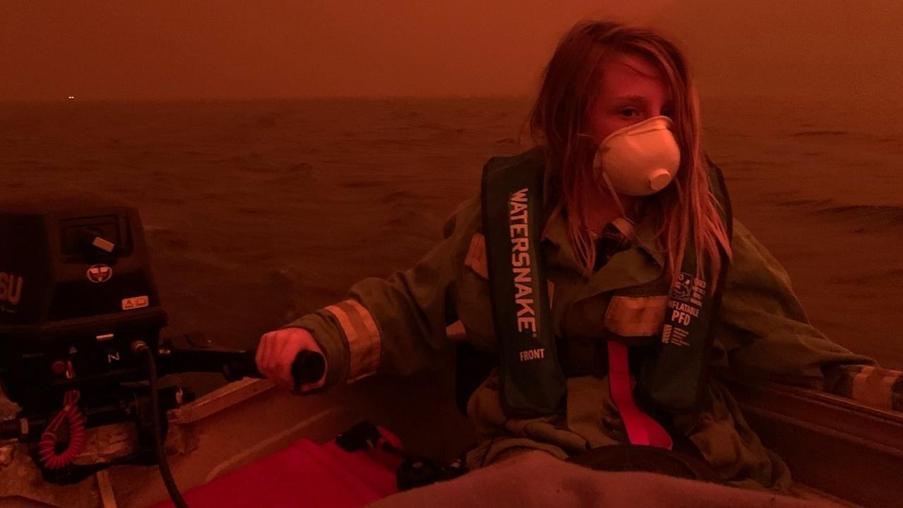 Finn Burns escapes the fires in a boat on Mallacoota lake in one of the most iconic images of the devastating bushfire season. Picture: ABC Gippsland